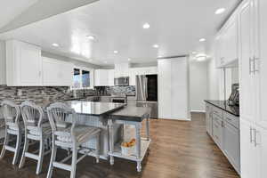Kitchen featuring a kitchen bar, a peninsula, stainless steel appliances, white cabinetry, and a textured ceiling