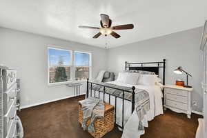 Bedroom with a ceiling fan and dark colored carpet