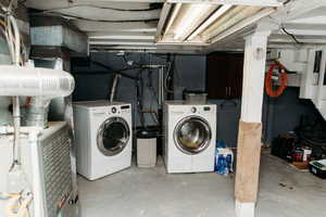 Laundry area featuring unfinished concrete floors, separate washer and dryer, and heating unit