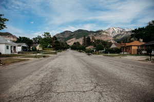 View of asphalt road featuring sidewalks, a residential view, curbs, and a mountain view