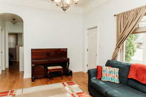 Living area featuring arched walkways, light wood-style flooring and crown molding