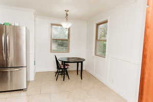 Dining space featuring a wainscoted wall, healthy amount of natural light,  light tile patterned floors, and crown molding