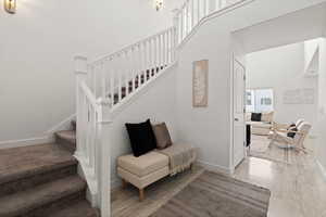 Staircase featuring carpet and LVP flooring, and high ceilings