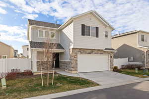 View of front of house featuring stone and Hardie siding, a 2-car garage, and a covered front porch