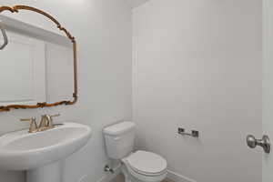 Half bath with decorative mirror, pedestal sink and toilet