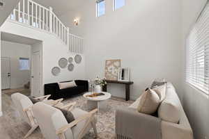 Living room featuring plenty of natural light, light LVP flooring, and two-story ceiling