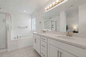 Primary ensuite bathroom featuring tile floors, dual sinks, quarts counters, and a separate tub and shower