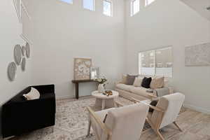 Living room featuring plenty of natural light, light LVP flooring, and two-story ceiling