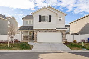 View of front of house featuring stone and Hardie siding, a 2-car garage, and a covered front porch