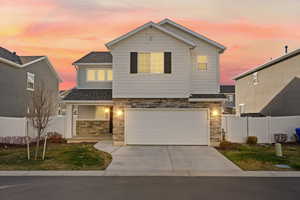 View of front of house featuring stone and Hardie siding, a 2-car garage, and a covered front porch