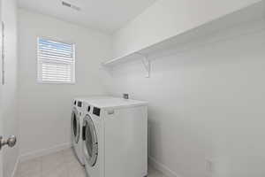 Second floor laundry room featuring tile floors and included front load washer & dryer