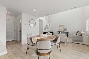 Semi-formal dining space featuring light LVP flooring and nearby access to the garage. The dining area is open to the spacious living room.