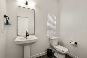 Half bathroom with baseboards and dark tile patterned flooring