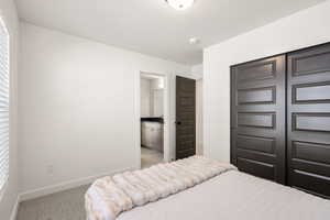 Bedroom featuring carpet, a closet, ensuite bathroom, and a textured ceiling