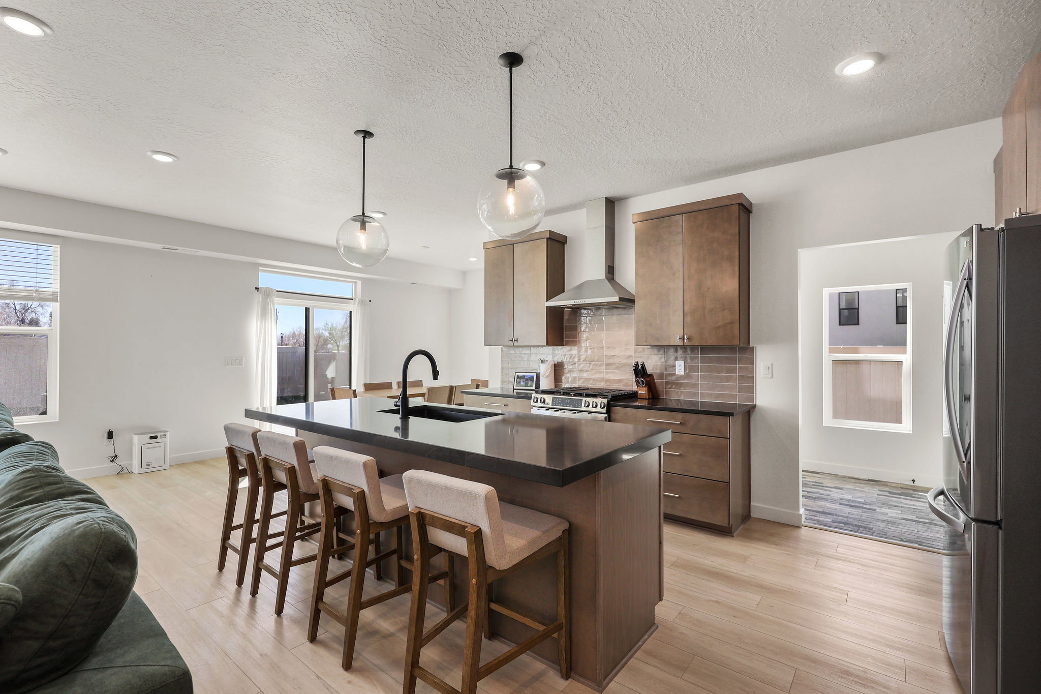 Kitchen with a breakfast bar, a center island with sink, stainless steel appliances, light wood finished floors, and decorative backsplash