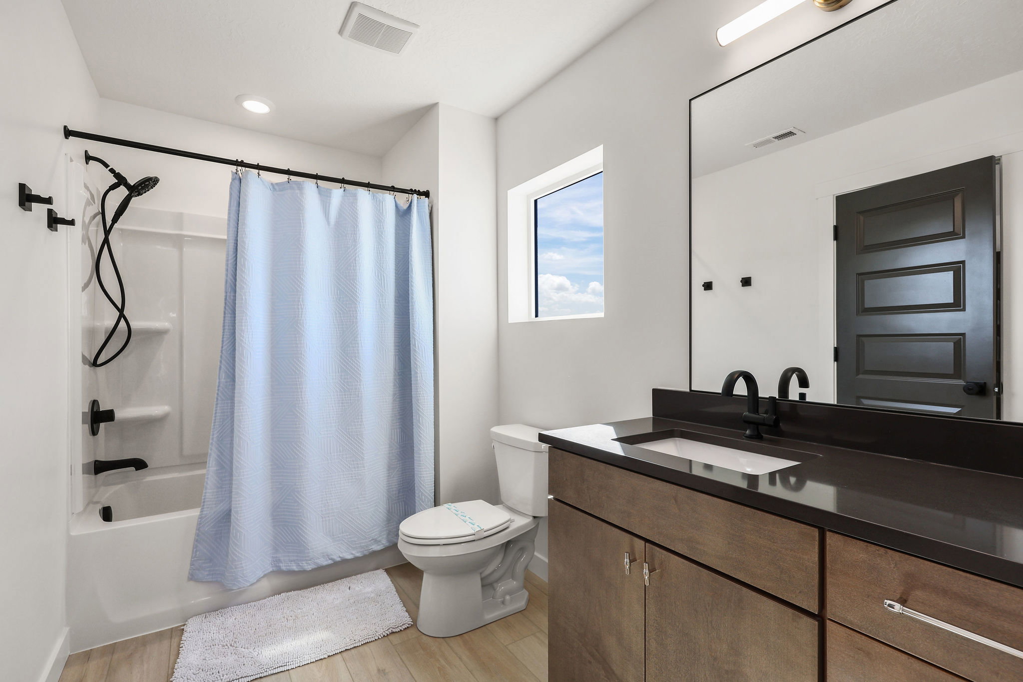 Bathroom featuring vanity, shower / tub combo, and light wood-type flooring