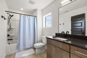 Bathroom featuring vanity, shower / tub combo, and light wood-type flooring