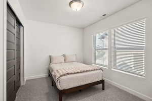 Carpeted bedroom with baseboards and a closet