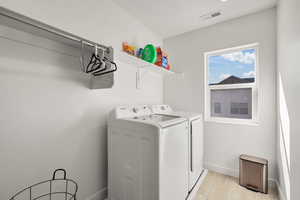 Laundry room with washing machine and dryer and light wood finished floors