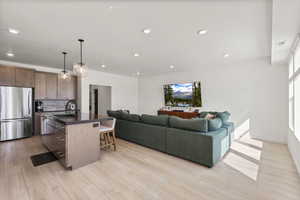Kitchen featuring stainless steel appliances, open floor plan, a kitchen island with sink, a breakfast bar, and tasteful backsplash