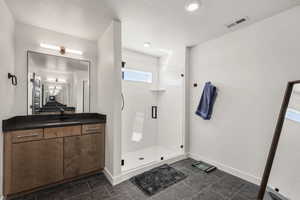 Bathroom featuring a shower stall, vanity, and a textured ceiling