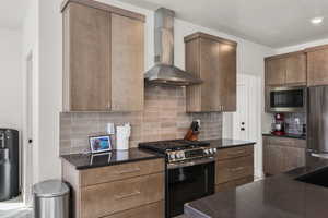 Kitchen featuring stainless steel appliances, a textured ceiling, decorative backsplash, and dark stone counters