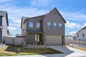 View of front of house featuring board and batten siding, an attached garage, and driveway