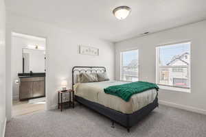 Bedroom featuring light carpet, ensuite bathroom, and a textured ceiling
