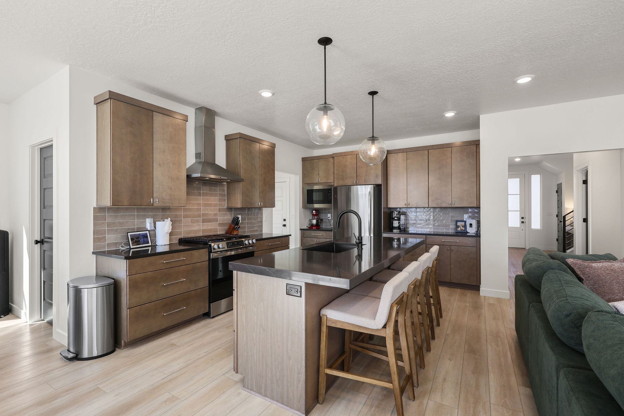 Kitchen featuring a kitchen breakfast bar, a center island with sink, stainless steel appliances, light wood-style flooring, and open floor plan