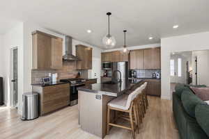 Kitchen featuring a kitchen breakfast bar, a center island with sink, stainless steel appliances, light wood-style flooring, and open floor plan