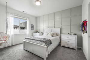 Bedroom with dark colored carpet and a decorative wall