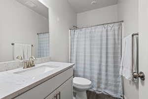 Full bath with vanity, curtained shower, dark wood-style flooring, and a textured ceiling