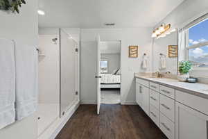 Ensuite bathroom featuring vanity, dark wood-type flooring, a stall shower, and a textured ceiling