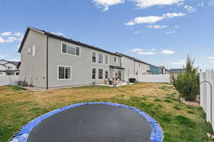 Rear view of property with a trampoline, a patio, a fenced backyard, and stucco siding