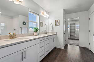 Bathroom with double vanity, dark wood-style floors, a walk in closet, tiled shower, and a textured ceiling