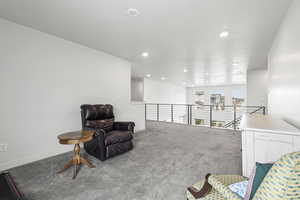 Living area featuring light carpet and an upstairs landing