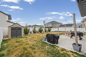 Fenced backyard featuring a shed, a residential view, a patio, and outdoor dining space