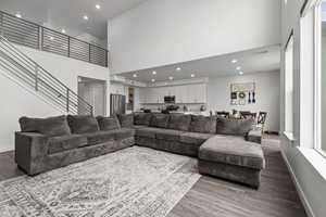 Living area with a high ceiling, wood finished floors, and recessed lighting
