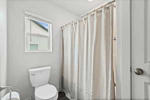 Bathroom featuring a shower with shower curtain and toilet