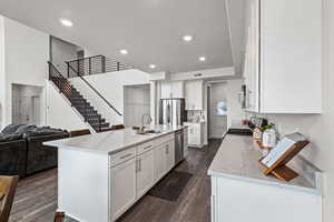 Kitchen with light stone countertops, open floor plan, white cabinets, stainless steel appliances, and recessed lighting