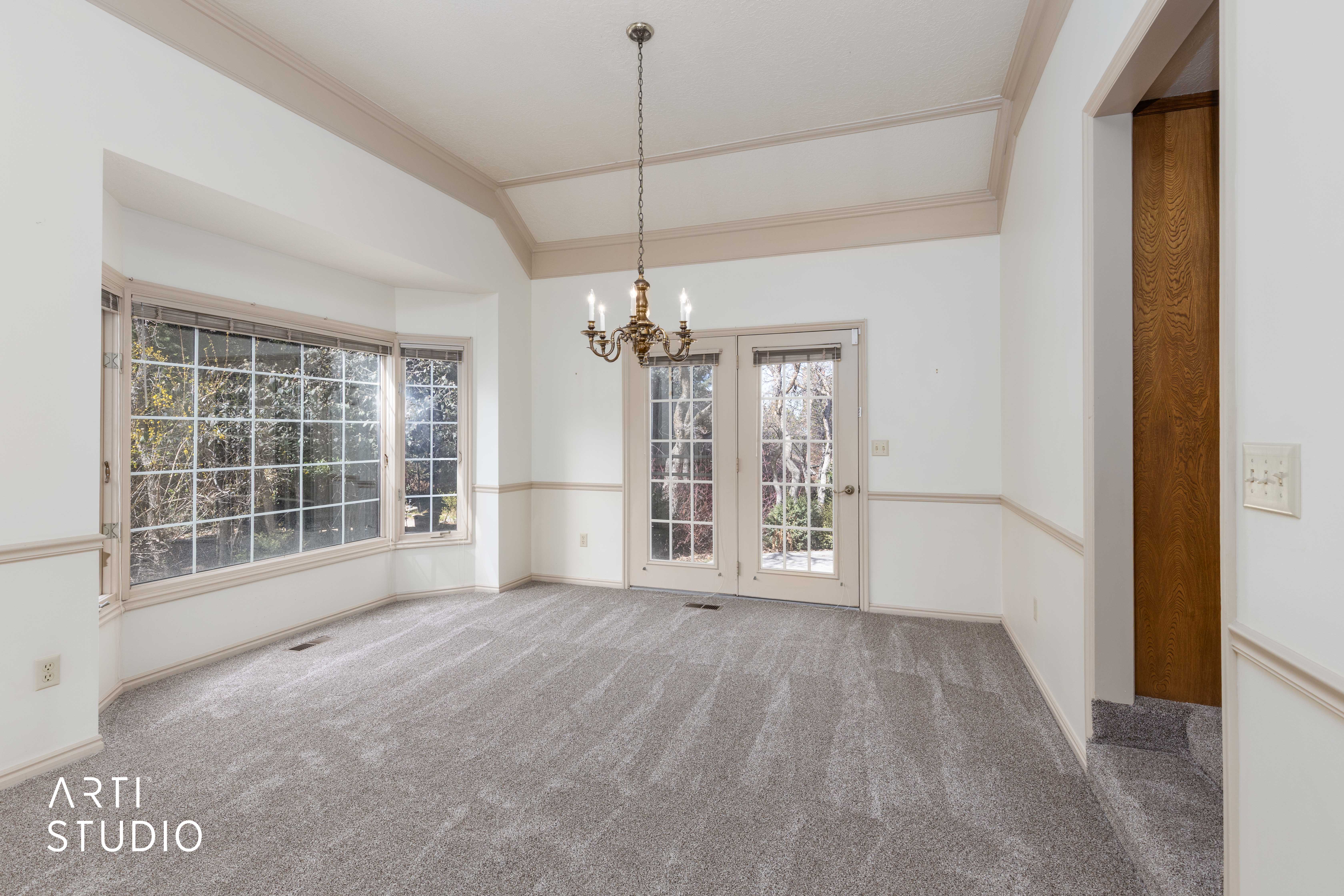 Unfurnished dining area featuring suspended lighting, ornamental molding, light carpet, and lofted ceiling