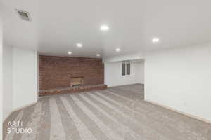 Finished basement with light carpet, a brick fireplace, and recessed lighting