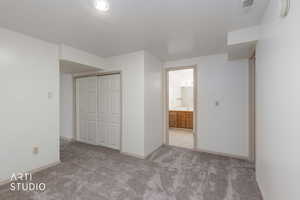 Unfurnished bedroom featuring light carpet, a closet, and ensuite bath