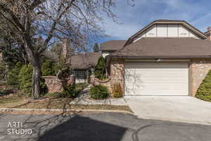 View of front of house with a shingled roof, brick siding, an attached garage, and concrete driveway