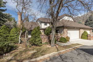 View of front facade featuring driveway, an attached garage, a shingled roof, brick siding, and stucco siding