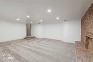 Finished basement with recessed lighting, light colored carpet, and a brick fireplace
