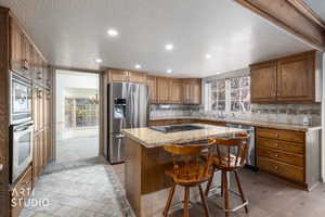 Kitchen featuring recessed lighting, wood finish cabinetry, backsplash, stainless steel appliances, and a center island