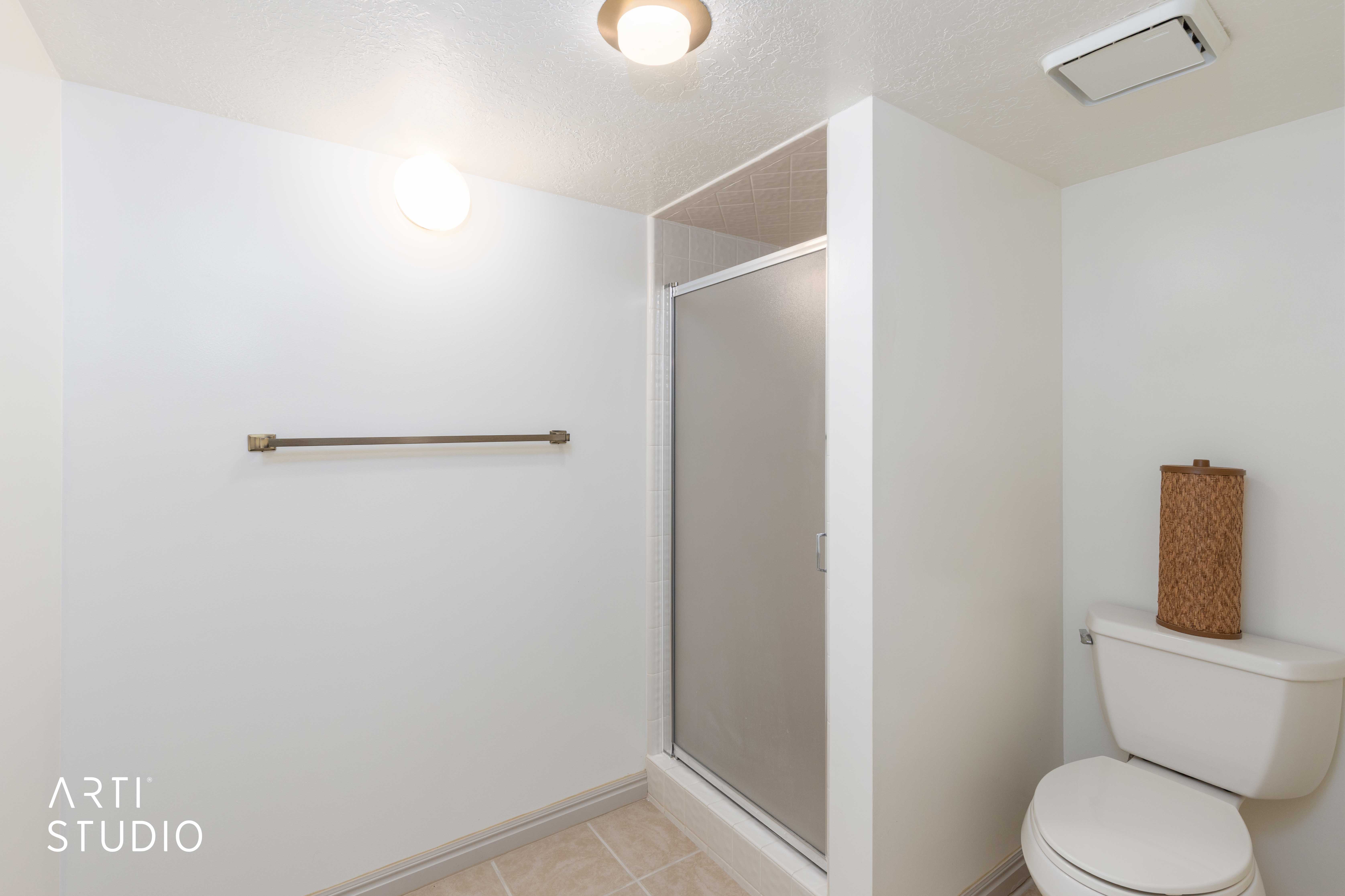 Bathroom with a textured ceiling, a stall shower, and light tile patterned floors