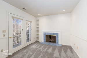 Main bedroom with built in shelves, a tile fireplace, and carpet floors