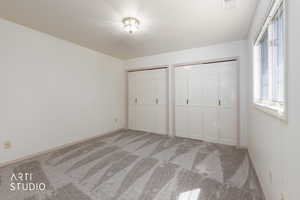 Unfurnished bedroom featuring multiple closets and light carpet